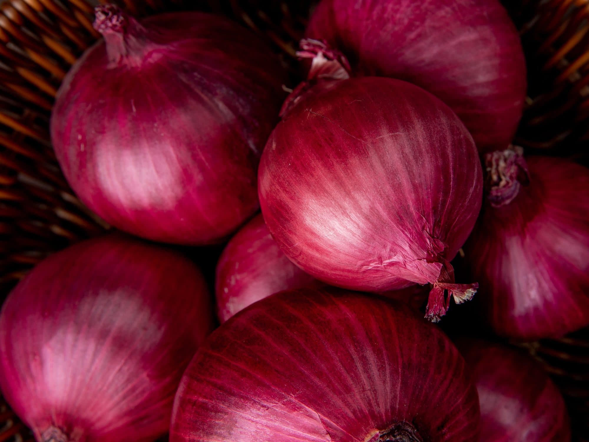 Red onions piled in a woven basket