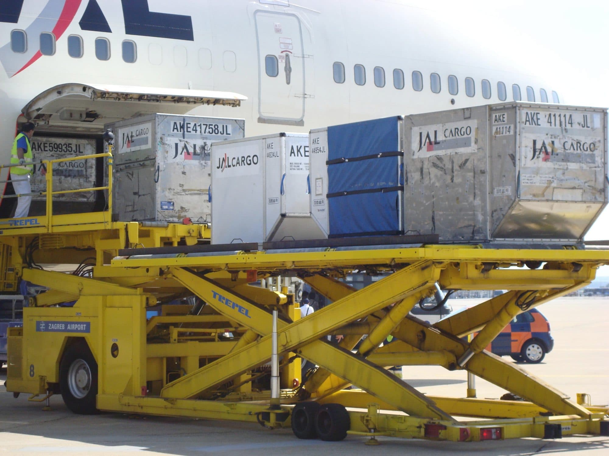 Air cargo containers on a loader beside a passenger jet